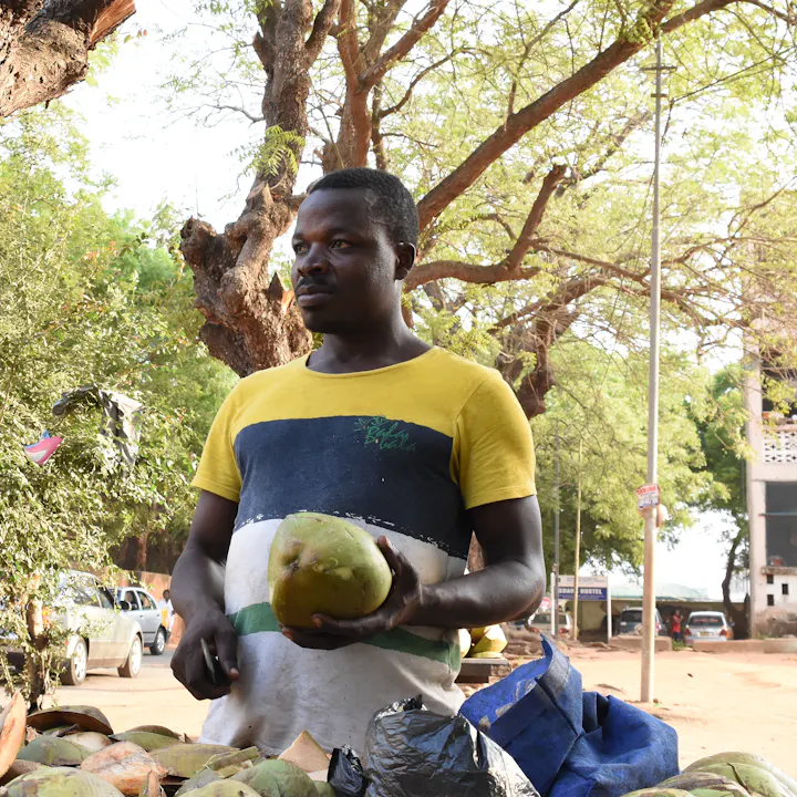 A vendor selling fresh coconuts by the road in Greater Accra